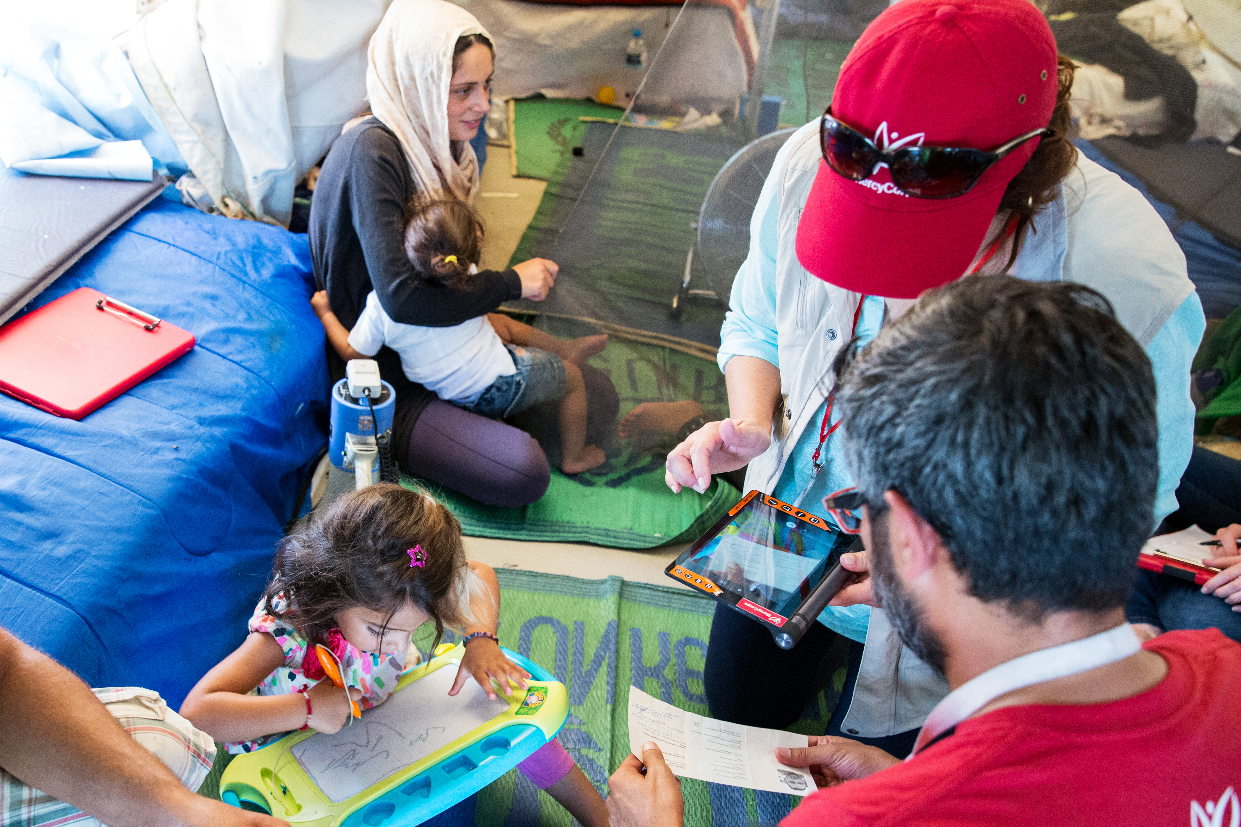Hassan and his family receive a cash transfer from Mercy Corps staff members in Katsikas camp, Ionnina