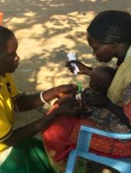 A CHW taking the MUAC of a child using the new, dual-red zone, MUAC tape