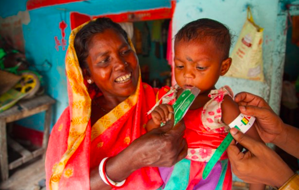 A child's MUAC is measured as her grandmother holds her by the CMAM District Coordinator Sudhakar, Bokaro, India, 2017