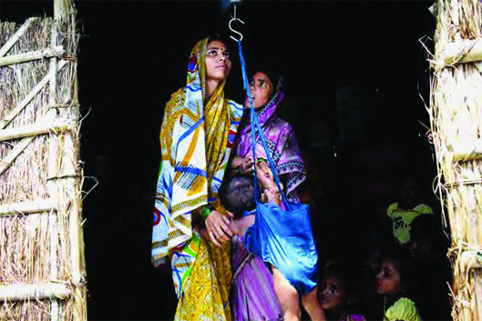 Workers at an anganwadi centre, which provides basic nutrition and health services, weigh an infant in Bihar, India
