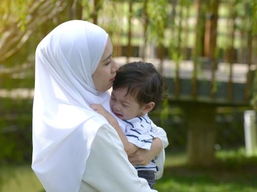 Malay mother carrying infant who is crying