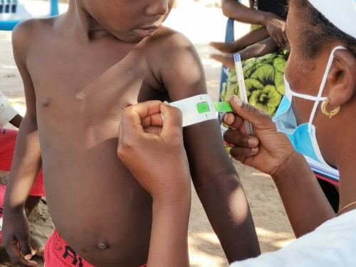 A boy's arm being measured for arm circumference by a medical professional