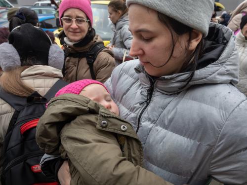 Syrian woman holding her child outside in refugee camp