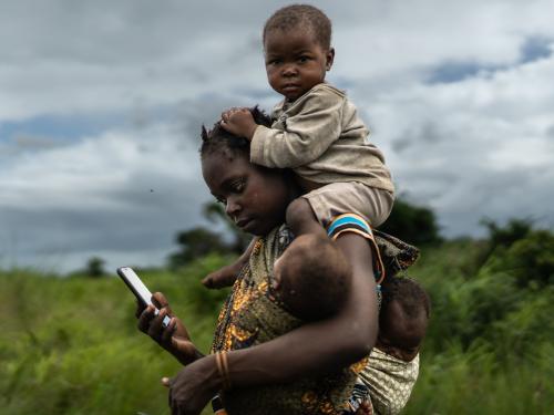 Mother looking at phone while carrying her two babies