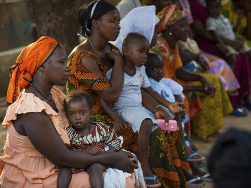 women and their babies sat in a line in a medical facility 