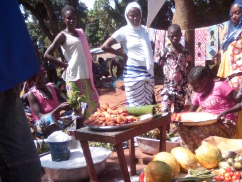 group stand outside behind tables laid with a variety of food