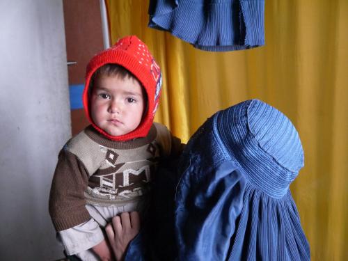 a child sat on someones shoulder looks into the camera
