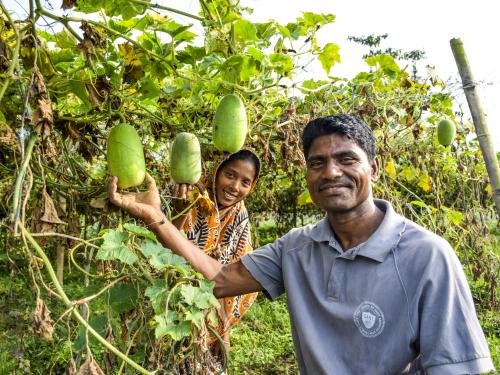 two figures pose next to a productive fruit tree