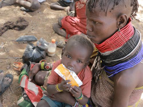 a child sat on a lap eats a packet of food