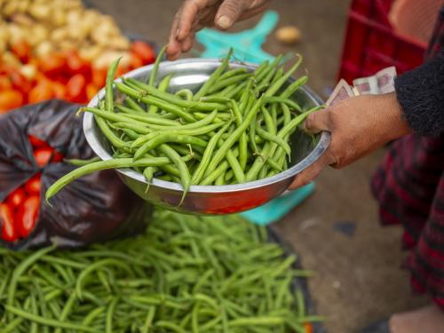 Someone holding a bowl of green beans in a market