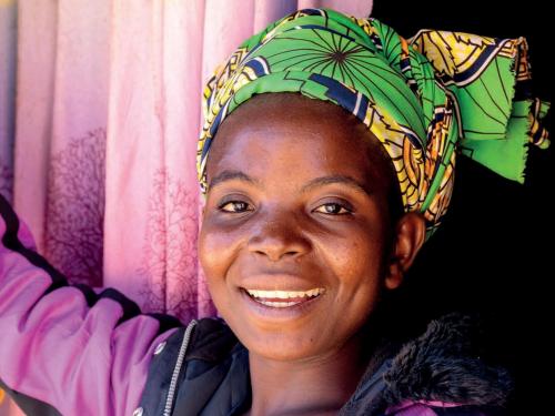 Front cover of technical briefing paper on women's nutrition titled, "Women's nutrition: a summary of evidence, policy and practice including adolescent and maternal life stages." The cover shows a woman standing and smiling at the camera.
