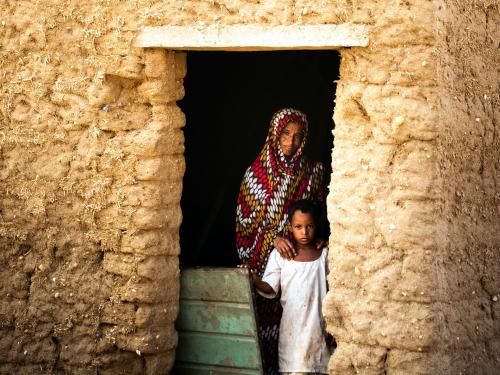 Woman and son in doorway to their house, rural Sudan