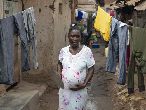 A pregnant woman passes by hanging clothes
