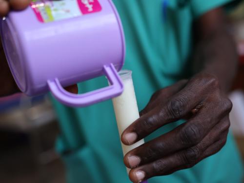 Close up of hands pouring milk from a cup into a tube
