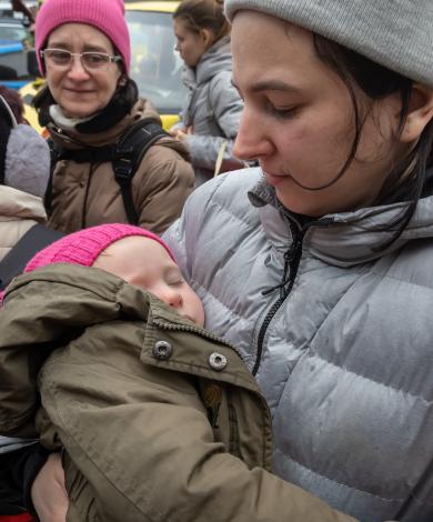 Syrian woman holding her child outside in refugee camp