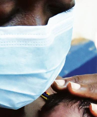 Photo of a woman wearing a mask while hugging her newborn baby
