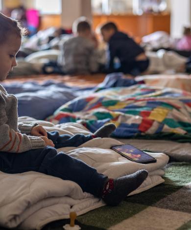 Boy sat alone on the ground in a refugee camp