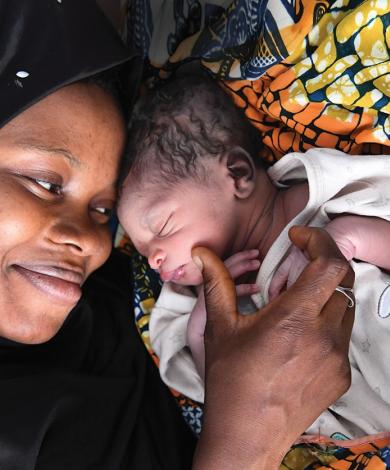 Image shows a mother cradling her new born baby. 