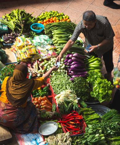 Woman selling fruit and vegetables at her outdoor market stall. 