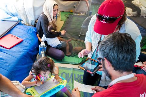 Hassan and his family receive a cash transfer from Mercy Corps staff members in Katsikas camp Ionnina