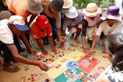 figures gathered round a mat placing photographs