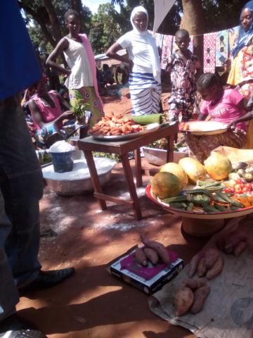 group stand outside behind tables laid with a variety of food
