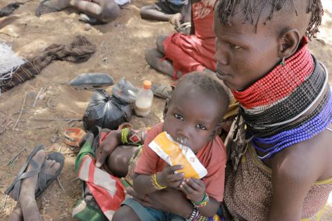a child sat on a lap eats a packet of food