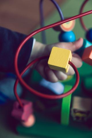child's hand playing with bead maze