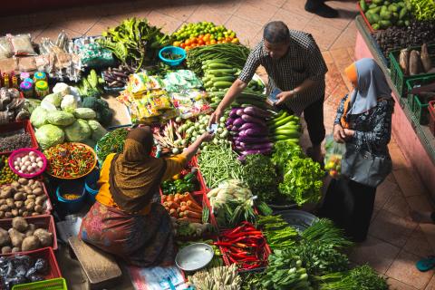 Woman selling fruit and vegetables at her outdoor market stall. 
