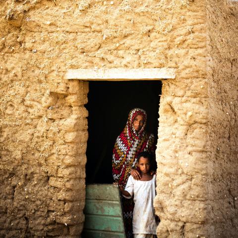 Woman and son in doorway to their house, rural Sudan