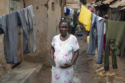 A pregnant woman passes by hanging clothes