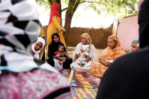 Women sit in a circle with their babies in their laps