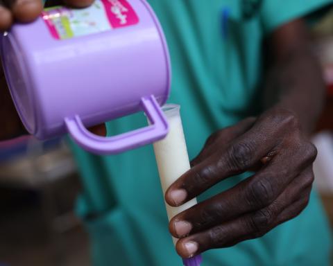 Close up of hands pouring milk from a cup into a tube